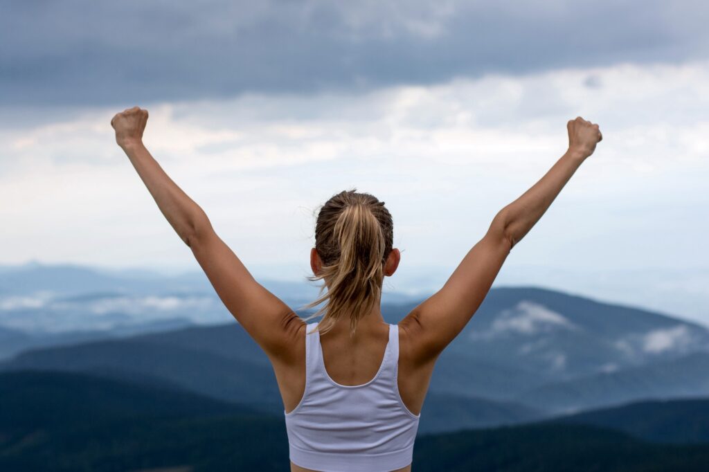 Young woman on top of the moutain with the arms raised enjoying freedom, Winner.
